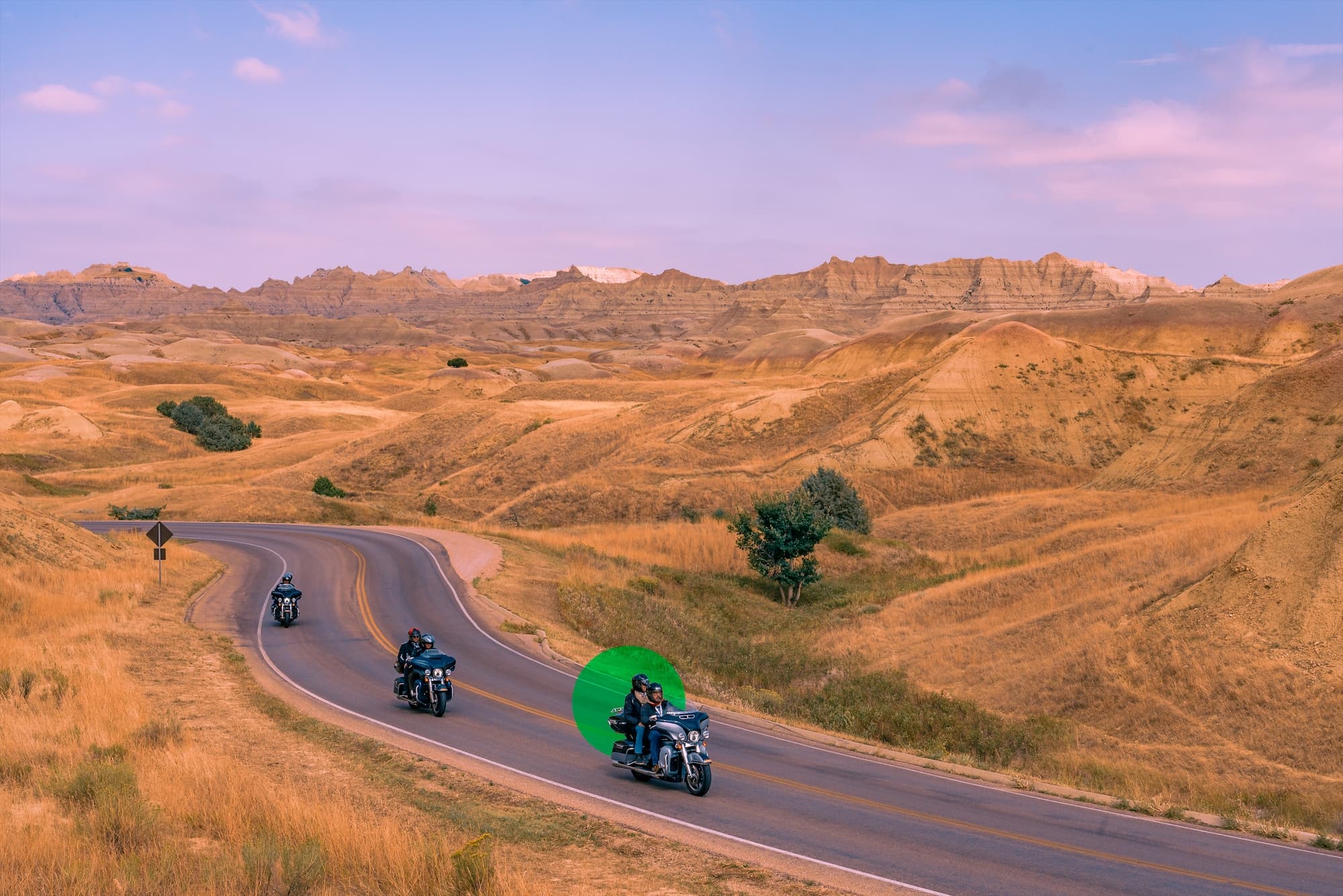 Group of motorcyclists riding on a scenic road with mountains in the background