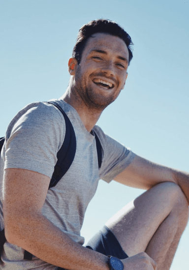 Smiling person wearing grey shirt and backpack
