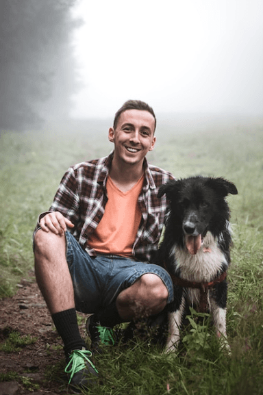 Man with border collie on misty trail
