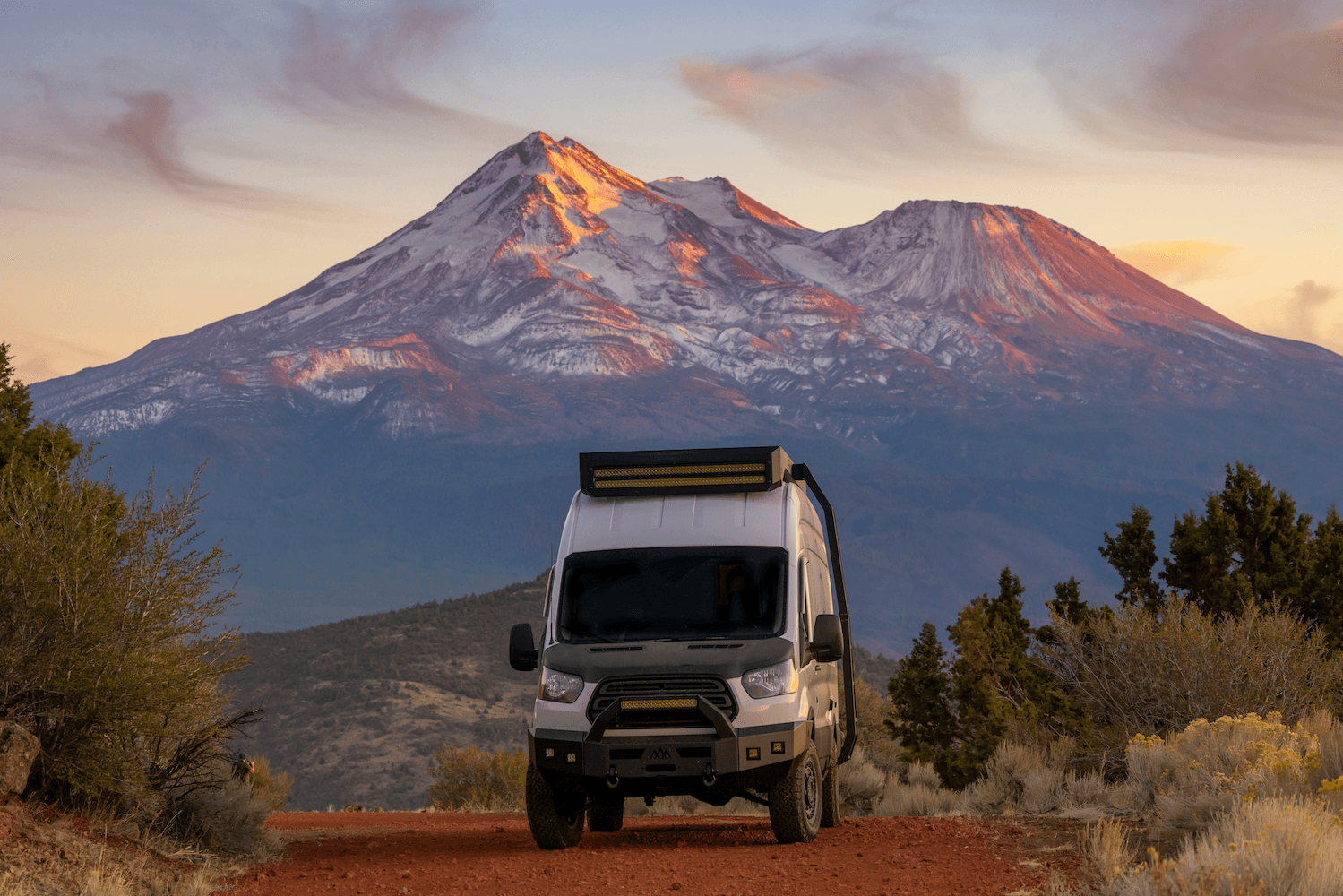 Large motorhome parked among tall evergreen trees in mountain forest